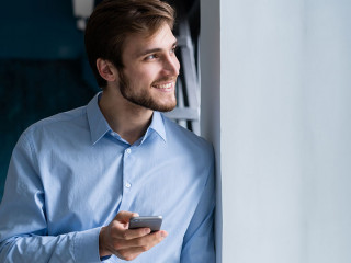 handsome young bearded business man in office using mobile phone indoors.
