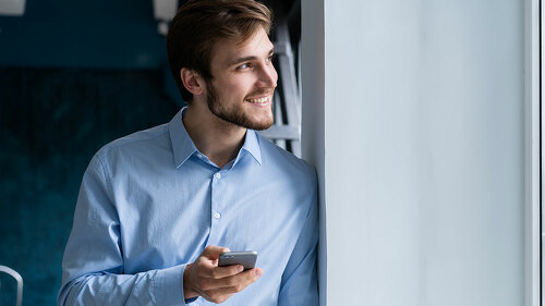handsome young bearded business man in office using mobile phone indoors.