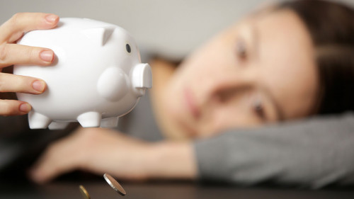 Unhappy woman shaking an empty piggy bank