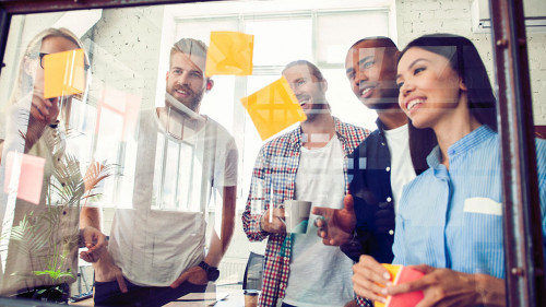 Business people meeting at office and use post it notes to share idea. Brainstorming concept. Sticky note on glass wall