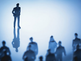 Single man standing in front of group of people.