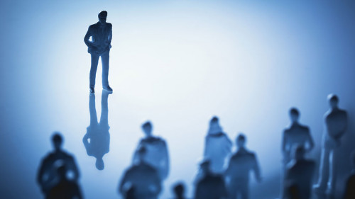 Single man standing in front of group of people.