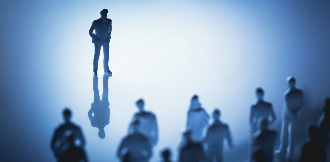 Single man standing in front of group of people.