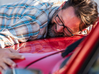 Handsome bearded man is hugging his new car and smiling - love f
