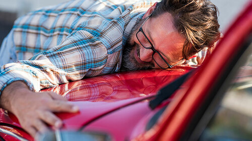 Handsome bearded man is hugging his new car and smiling - love f