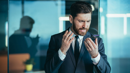 Angry and nervous boss shouting into phone, during phone conversation with employee, businessman in modern office with phone