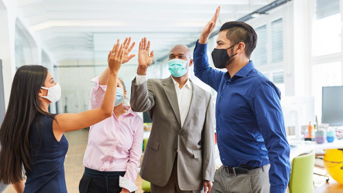 Business Team mit Mund-Nasen-Schutz beim High Five