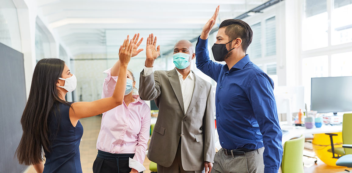 Business Team mit Mund-Nasen-Schutz beim High Five