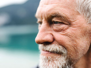 A close-up portrait of senior man pensioner standing outdoors in nature.
