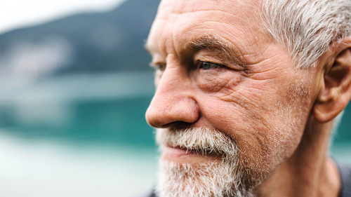 A close-up portrait of senior man pensioner standing outdoors in nature.