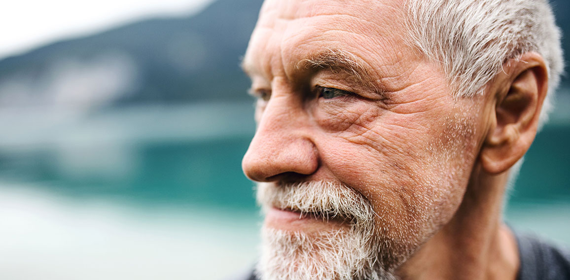 A close-up portrait of senior man pensioner standing outdoors in nature.