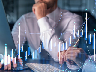 Two colleagues in formal wear working together to optimize trading strategy at corporate finance fund. Forex chart hologram over modern office background