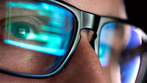 Developer coder looking on computer, programming code reflecting in glasses.