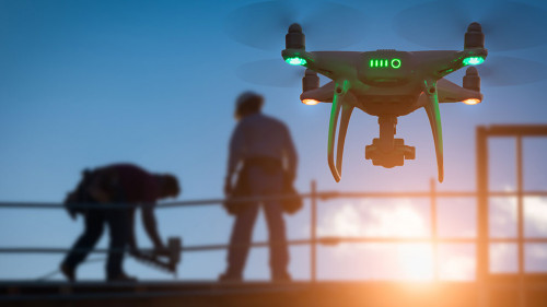 Silhouette of Unmanned Aircraft System Drone (UAV) Quadcopter Drone In The Air Over Building Under Construction.