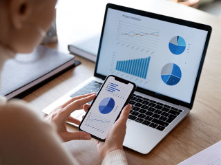 Businesswoman using smartphone and laptop, sales statistics on devices screens