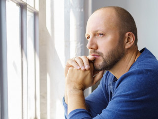 geschäftsmann steht im büro und schaut nachdenklich aus dem fenster