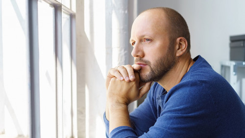 geschäftsmann steht im büro und schaut nachdenklich aus dem fenster