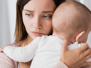 worried mother holding in arms baby boy and looking away