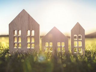 Ecological wood model house in empty field at sunset