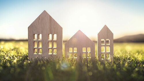 Ecological wood model house in empty field at sunset