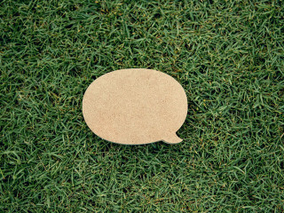 Blank yellow speech bubble pin on green grass background