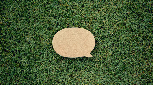Blank yellow speech bubble pin on green grass background