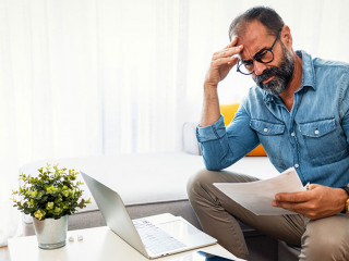 Confused frustrated mature man holding mail letter and money, re