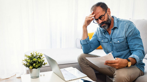 Confused frustrated mature man holding mail letter and money, re