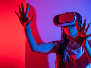 Young woman using glasses of virtual reality on dark background.
