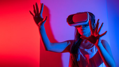 Young woman using glasses of virtual reality on dark background.