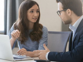 Female manager broker consulting client in corporate office with laptop