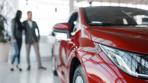 Couple buying new red car in showroom