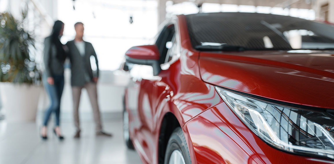 Couple buying new red car in showroom