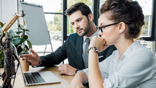lawyers discussign work at workplace with laptop and femida in o