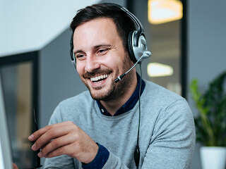 Casual smiling businessman with headset at work in modern office
