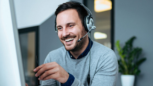Casual smiling businessman with headset at work in modern office