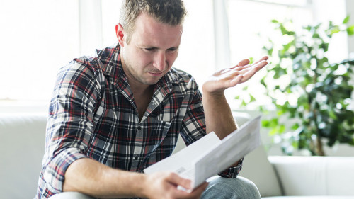 Shocked man holding some documents on sofa livingroom