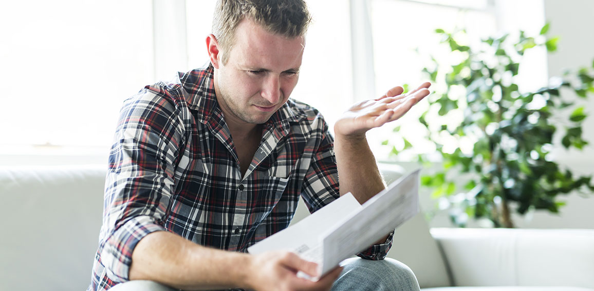 Shocked man holding some documents on sofa livingroom