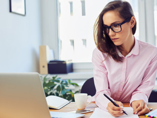 Busy oung woman working in office with documents and laptop