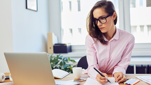 Busy oung woman working in office with documents and laptop