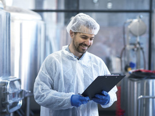 Industrial worker technologist in white suit with hairnet and pr