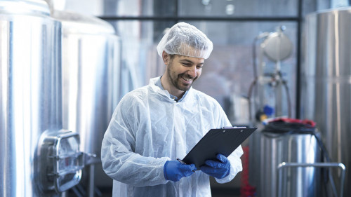 Industrial worker technologist in white suit with hairnet and pr