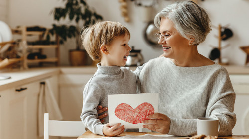 happy family grandson child congratulates grandmother on holiday and gives card