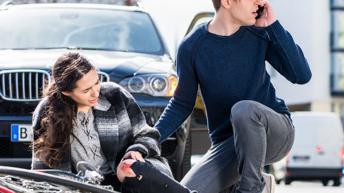 Young man calling the emergency services after hitting a bicyclist