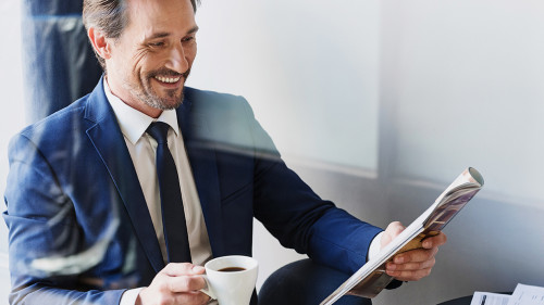 Cheerful businessman drinking coffee in cafe