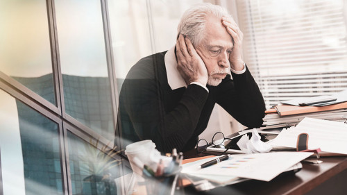 Overworked businessman sitting at a messy desk; multiple exposur