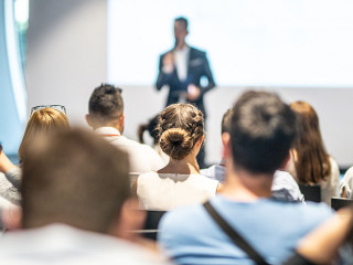 Male business speaker giving a talk at business conference event.