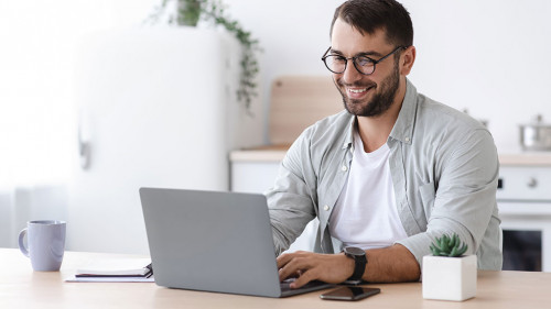 Happy handsome mature european male teacher or businessman with beard in glasses working at laptop
