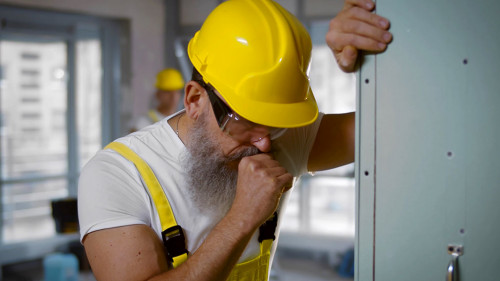Senior construction worker sick and coughing in renovating apartment