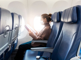 A young woman wearing face mask is traveling on airplane , New normal travel after covid-19 pandemic concept